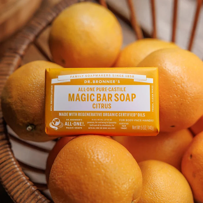 A bar of Dr. Bronners Magic Bar Soap Citrus rests among oranges in a wooden basket. The vibrant soap packaging contrasts with the natural backdrop, highlighting organic ingredients and eco friendly ethos. Dr. Bronners All One Magic Bar Soap Citrus, Made with Organic Oils [5 oz]