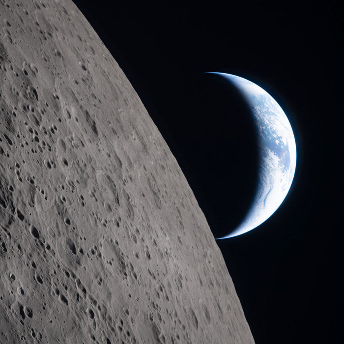 A crescent Earth setting on the lunar limb photographed by the Artemis II crew, with Ohm crater in the foreground